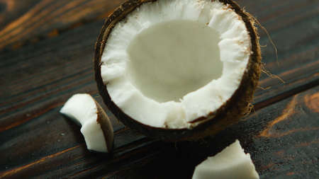 From above cracked ripe coconut with white flesh on dark wooden backgroundの写真素材