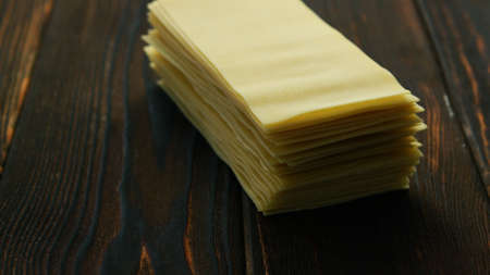 Closeup of stacked uncooked sheets for lasagna cooking composed on wooden table surfaceの写真素材