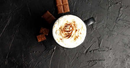 Top view of mug with cacao and white whipped cream powdered with cacao and served on table with milk...