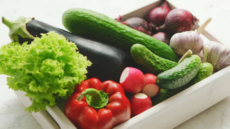 From above of box filled with various fresh vegetables in daylight