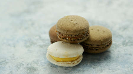 Closeup of white and chocolate macarons with different fillings composed in small heap on marble...