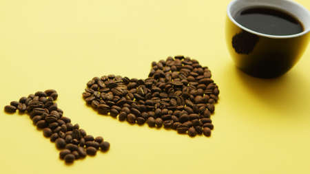 Arrangement of roasted brown coffee beans with cup of black coffee composed in phrase I love coffee...