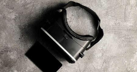 From above shot of black modern headset gadget of virtual reality lying on rough gray background...
