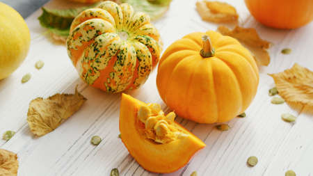 From above view of orange ripe pumpkins laid on wooden background and decorated with withered leaves