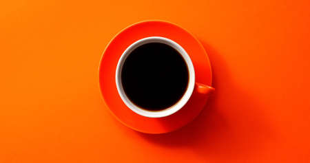 From above view of cup with black coffee placed on orange backgroundの写真素材