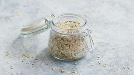 Small glass jar full of oats composed on marble surface of table in daylightの写真素材