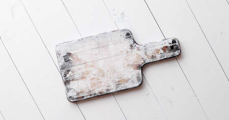 Handmade wooden chopping board on white board table.