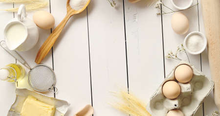 From above shot of various cooking tools and fresh pastry ingredients forming nice border on white...