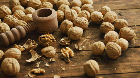 Closeup shot of fresh walnuts and wooden tool for cracking nuts lying on lumber tabletop