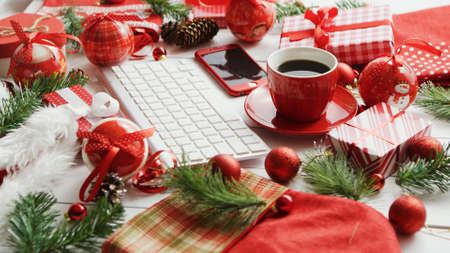 Various symbols of Christmas lying on table around cup of aromatic hot drink and modern devicesの写真素材