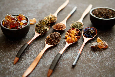 Spoons with different types of dry tea leaves on rusty dark background. Top view.の写真素材