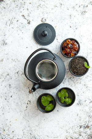 Traditional eastern metal teapot and iron cups with mint tea leafs over the white rusty stone backgroundの写真素材