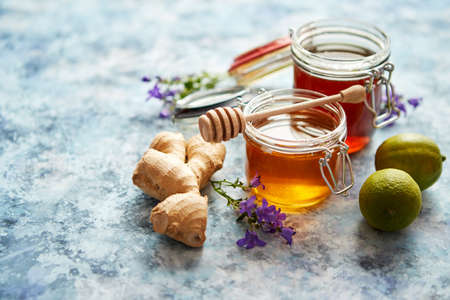 Healthy food table with different kinds of honey, fresh ginger and lime. Placed on stone table with copy space.の写真素材