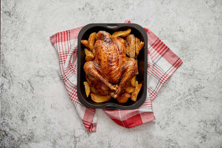 Roasted chicken or turkey with potatoes in black steel mold placed on napkin, flat lay with copy space on stone background. Top view.の写真素材