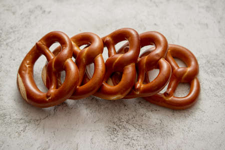 Row of fresh baked brown salty pretzel bread. Placed on stone background. Shot from above with copy...