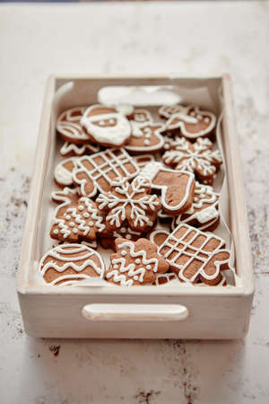 Collection of various shaped gingerbread Christmas cookies placed in white wooden crate. White rusty...