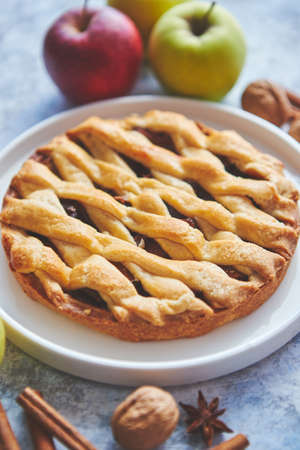 Fresh and tasty sweet homemade apple pie cake with cinnamon sticks, walnuts and apples on side. Placed on stone background.の写真素材
