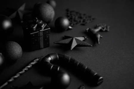 Christmas minimalistic and simple composition in mat black color. Christmas gifts, decorations on black background. Flat lay, top view with copy spaceの写真素材