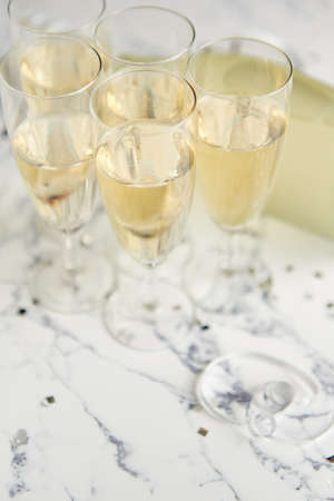 Champagne glasses and bottle placed on white marble background. Party and holiday celebration concept with confetti and serpentines. With copy space.の写真素材