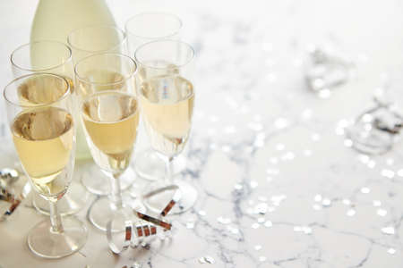 Champagne glasses and bottle placed on white marble background. Party and holiday celebration concept with confetti and serpentines. With copy space.の写真素材