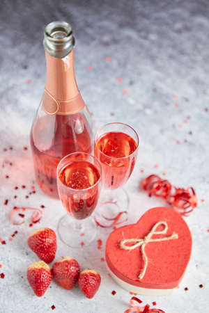 Bottle of rose champagne, two glasses with fresh ripe strawberries and heart shaped boxed gift, placed on stone table for a special romantic occasion or Valentines. With copy spaceの写真素材
