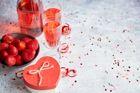 Bottle of rose champagne, two glasses with fresh ripe strawberries and heart shaped boxed gift, placed on stone table for a special romantic occasion or Valentines. With copy spaceの写真素材