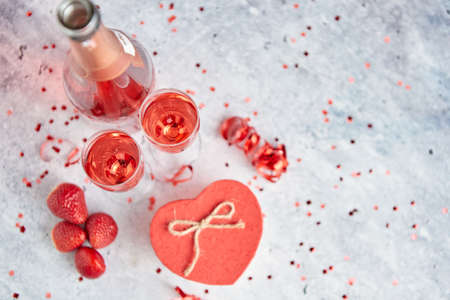 Bottle of rose champagne, two glasses with fresh ripe strawberries and heart shaped boxed gift, placed on stone table for a special romantic occasion or Valentines. With copy spaceの写真素材