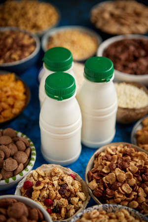 Assortment of various kinds cereals placed in ceramic bowls with cornflakes, granola, cereals,...
