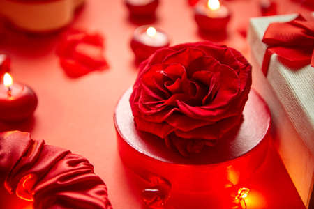Valentines day romantic decoration with roses, boxed gifts, candles, on a red background table. Top view, copy space.の写真素材
