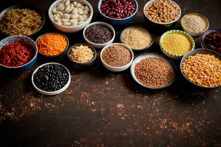 Various superfoods in smal bowls on dark rusty background. Superfood as rice, lentil, beans, peas, goji, flaxseed, buckwheat, couscous, chickpeas Copy space for textの写真素材