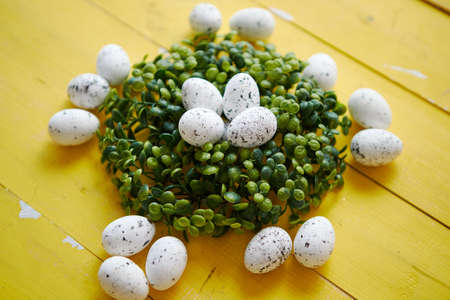 Green decorative Easter quail eggs wreath on yellow wooden table background. Top angle shot. Flat lay.の写真素材