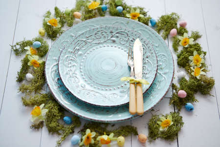 Easter table setting with flowers and eggs. Empty decorative ceramic plates. Rustical dishware. View from above.の写真素材
