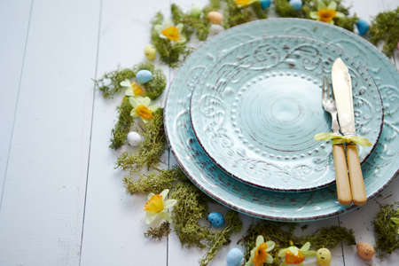 Easter table setting with flowers and eggs. Empty decorative ceramic plates. Rustical dishware. View from above.の写真素材