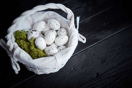 Quail eggs in a nest on a black rustic wooden background. Easter symbols or Healthy food concept.