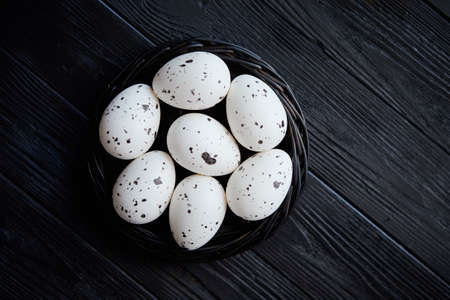 Whole Chicken eggs in a nest on a black rustic wooden background. Easter symbols or Healthy food concept.の写真素材