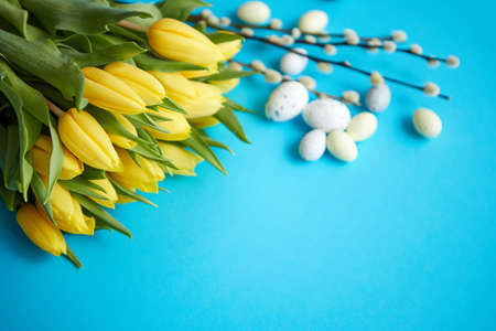 Holiday contept decoration with easter eggs and yellow tulips over blue background. Top view with copy space.の写真素材