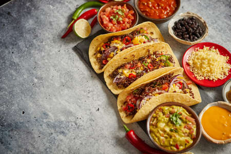 Tasty Mexican meat tacos served with various vegetables and salsa. With sides in ceramic bowls around. Top view composition. Space for text.の素材 [FY310123798406]