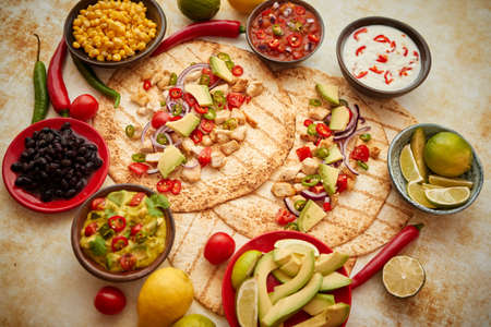 Freshly made healthy corn tortillas with grilled chicken fillet, big avocado slices, fresh salsa, limes and differend sides. Placed on rusty table. Healthy food, gluten-free, allergy-friendly, weight loss conceptの写真素材