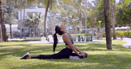 Side view of meditated relaxed Asian woman in fitness clothing performing stretching raising neck in park Thailand, Phuketの写真素材