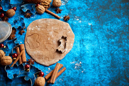 Christmas baking concept. Gingerbread dough with different cutter shapes and spices on sides. Top view on blue rustic background.の写真素材
