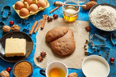 Ready for next step raw gingerbread dough placed among various ingredients. Christmas baking concept. Placed on blue background. View from above.の写真素材