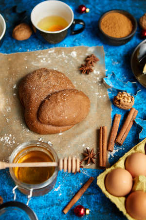 Ready for next step raw gingerbread dough placed among various ingredients. Christmas baking concept. Placed on blue background. View from above.の写真素材