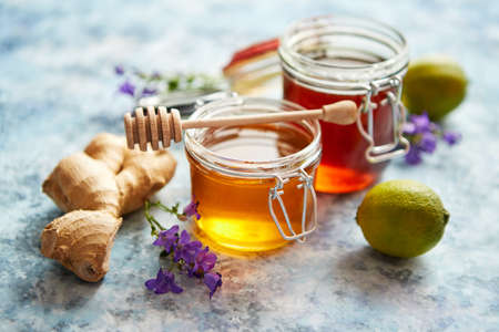 Healthy food table with different kinds of honey, fresh ginger and lime. Placed on stone table with copy space.の写真素材