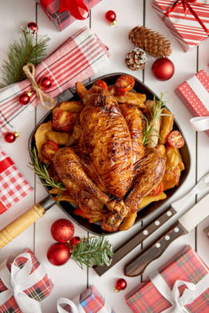 Roasted whole chicken or turkey served in iron pan with beautiful Christmas decoration. Placed on white rustical wooden background. Top view.の写真素材