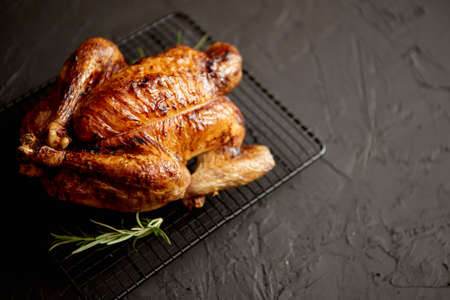 Homemade baked chicken with rosemary herbs. Served on steel black grill frame. Black stone background, Shot from above.の写真素材