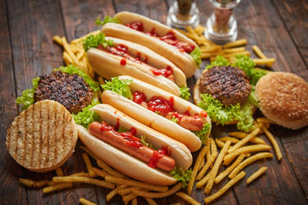 Fastfood assortment. Hamburgers and hot dogs placed on rusty wood table. Served with french fries. View from above.の写真素材
