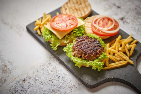 Two tasty grilled home made burgers with beef, tomato, onion and lettuce. French frides on side. Top view with copy spaceの写真素材