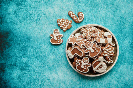 Rustical plate filled with delicous, varous Christmas shaped gingerbread cookies. Top view. Placed on blue rustic background.の写真素材
