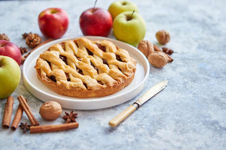 Tasty sweet homemade apple pie cake with cinnamon sticks, walnuts and apples on side. Placed on stone background with copy space.の写真素材