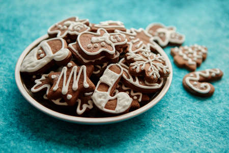 Rustical plate filled with delicous, varous Christmas shaped gingerbread cookies. Top view. Placed on blue rustic background.の写真素材